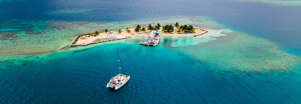 Belize blog header - catamaran anchored off island with reef